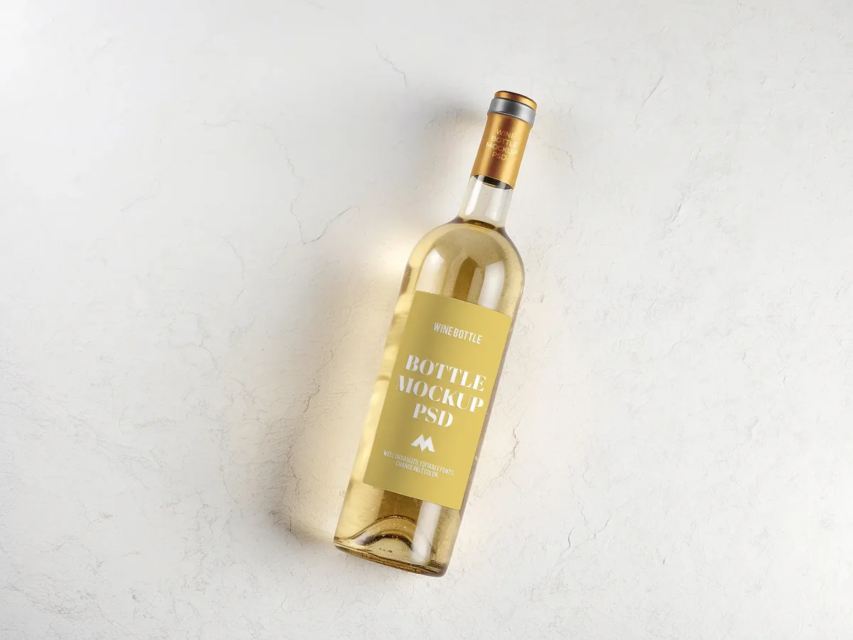 White wine bottle mockup with gold cap and gold Wine Bottle Mockup PSD label, tilted on a marble surface with a warm light streak.