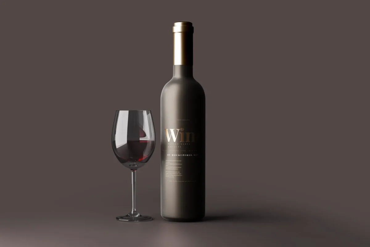 Matte dark wine bottle with gold cap and gold foil Wine label, beside a glass of red wine, on a plain brown background.