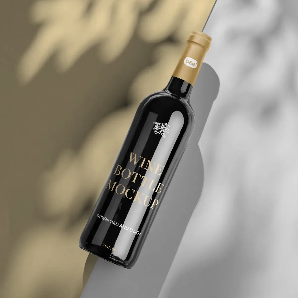 Dark wine bottle with gold foil Wine Bottle Mockup label, tilted diagonally against a two-tone wall corner with dappled leaf-shadow lighting.