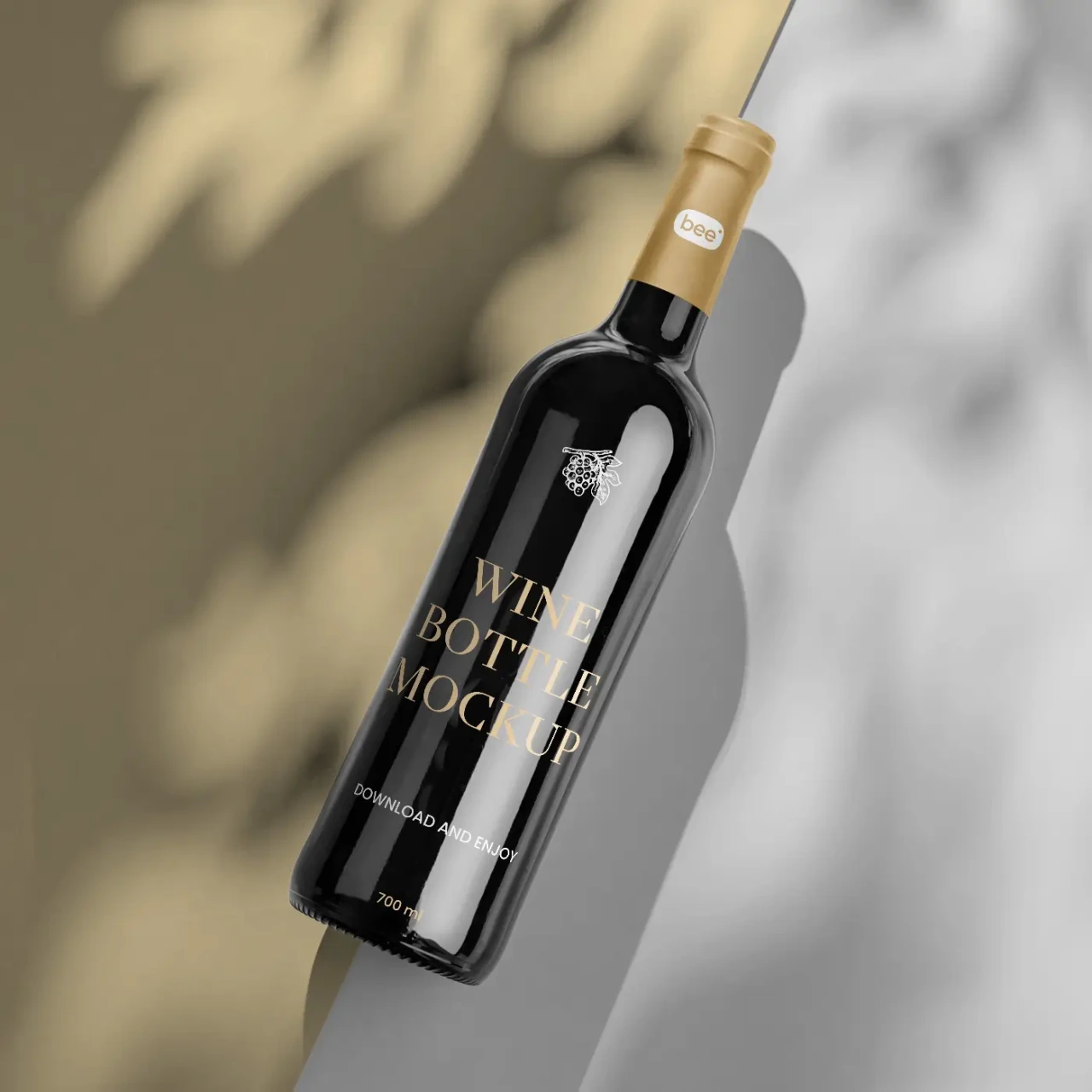 Dark wine bottle with gold foil Wine Bottle Mockup label, tilted diagonally against a two-tone wall corner with dappled leaf-shadow lighting.
