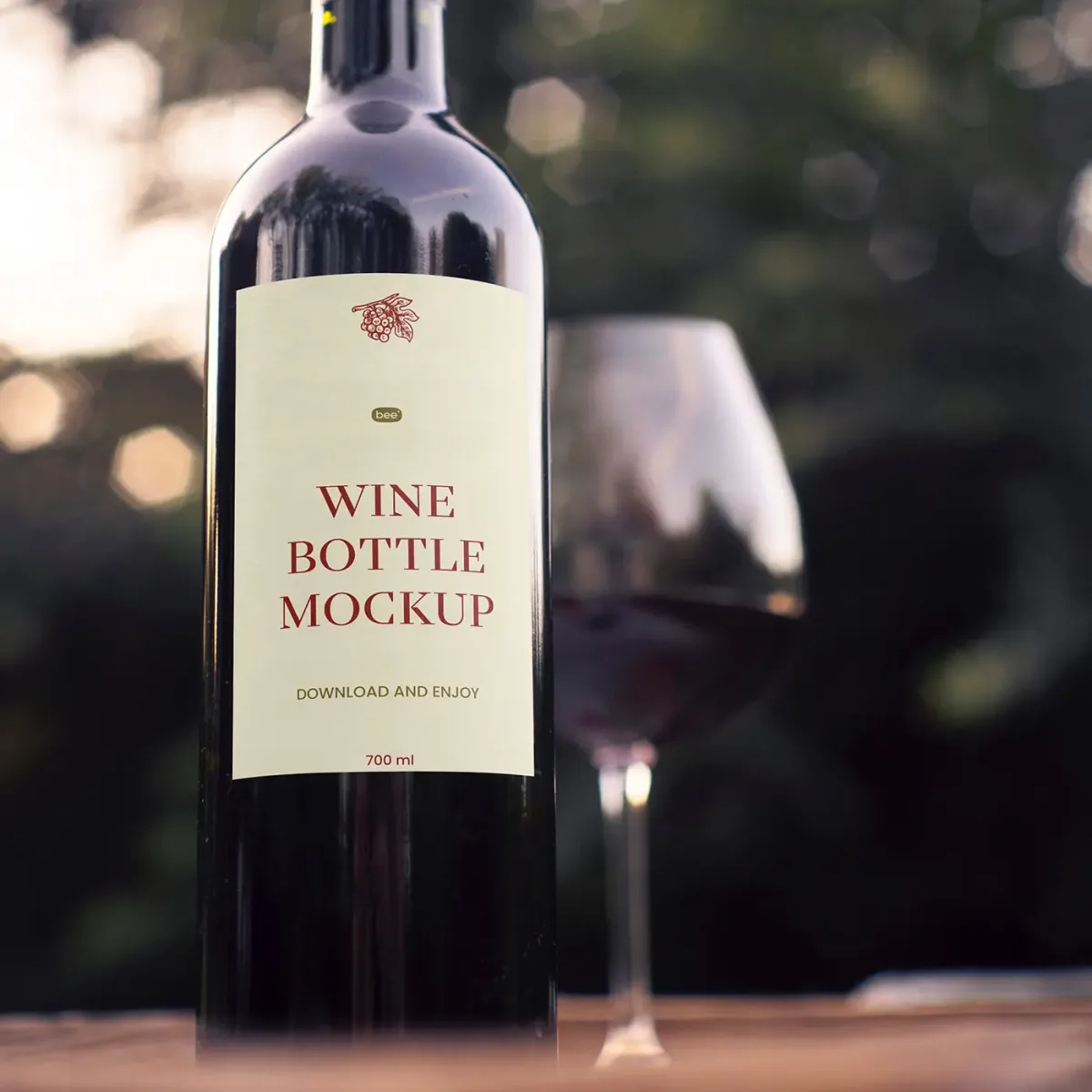 Close-up of a wine bottle labelled Wine Bottle Mockup, with a poured wine glass blurred in the background, outdoor bokeh lighting.